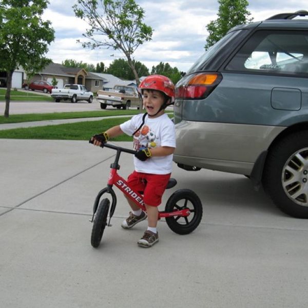Little boy in driveway riding a red Strider