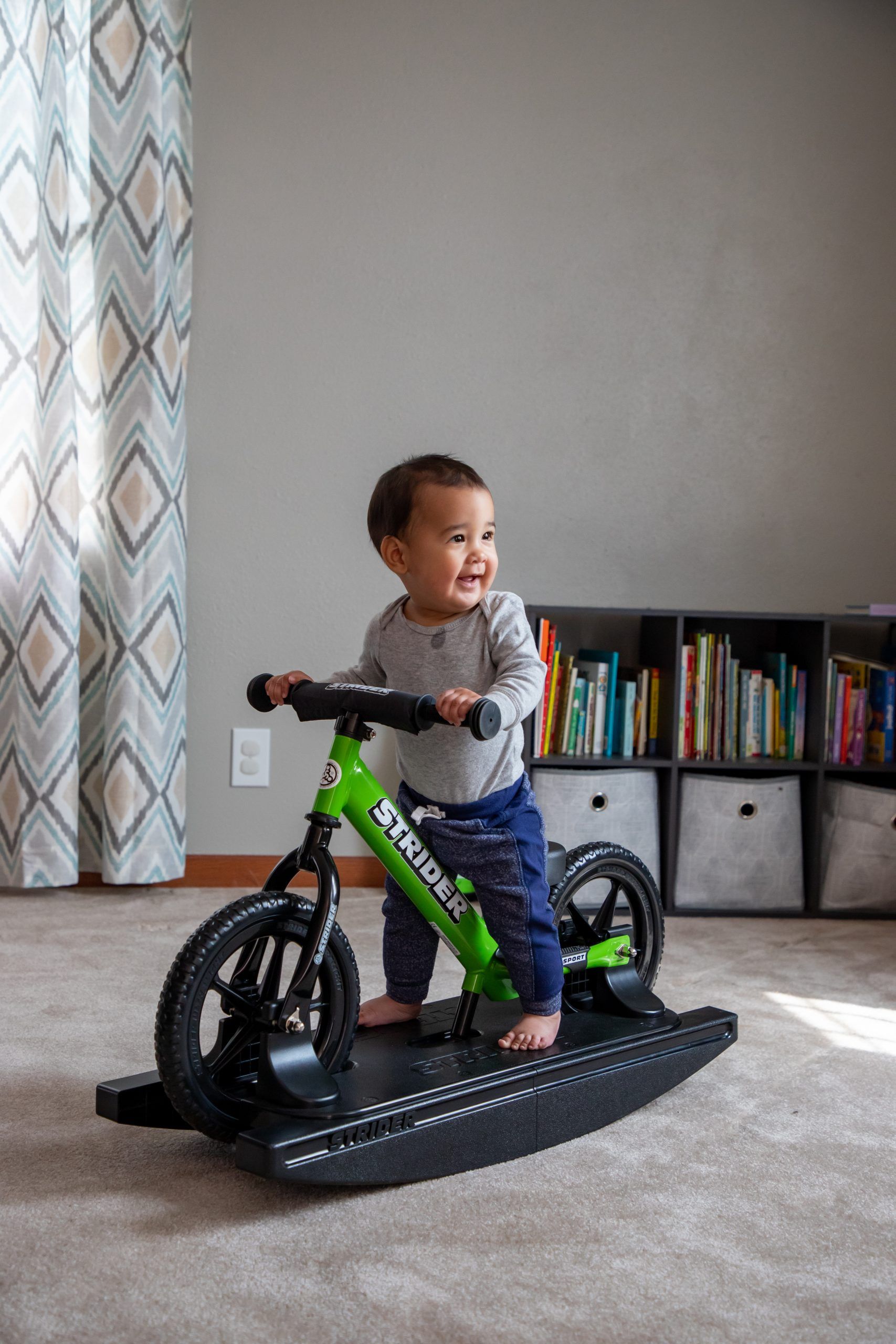 Boy plays on a green 12 Sport 2-in-1 Rocking Bike in a living room