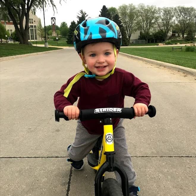 Owen Tudor, a young boy, rides his yellow Strider bike