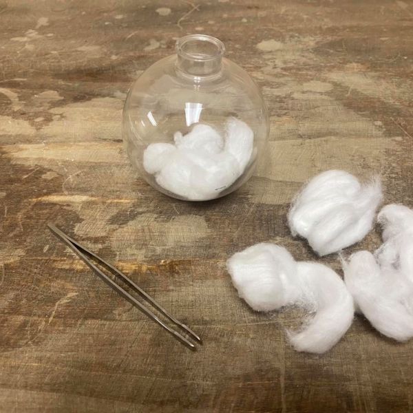 Filling a glass ornament with cotton balls 