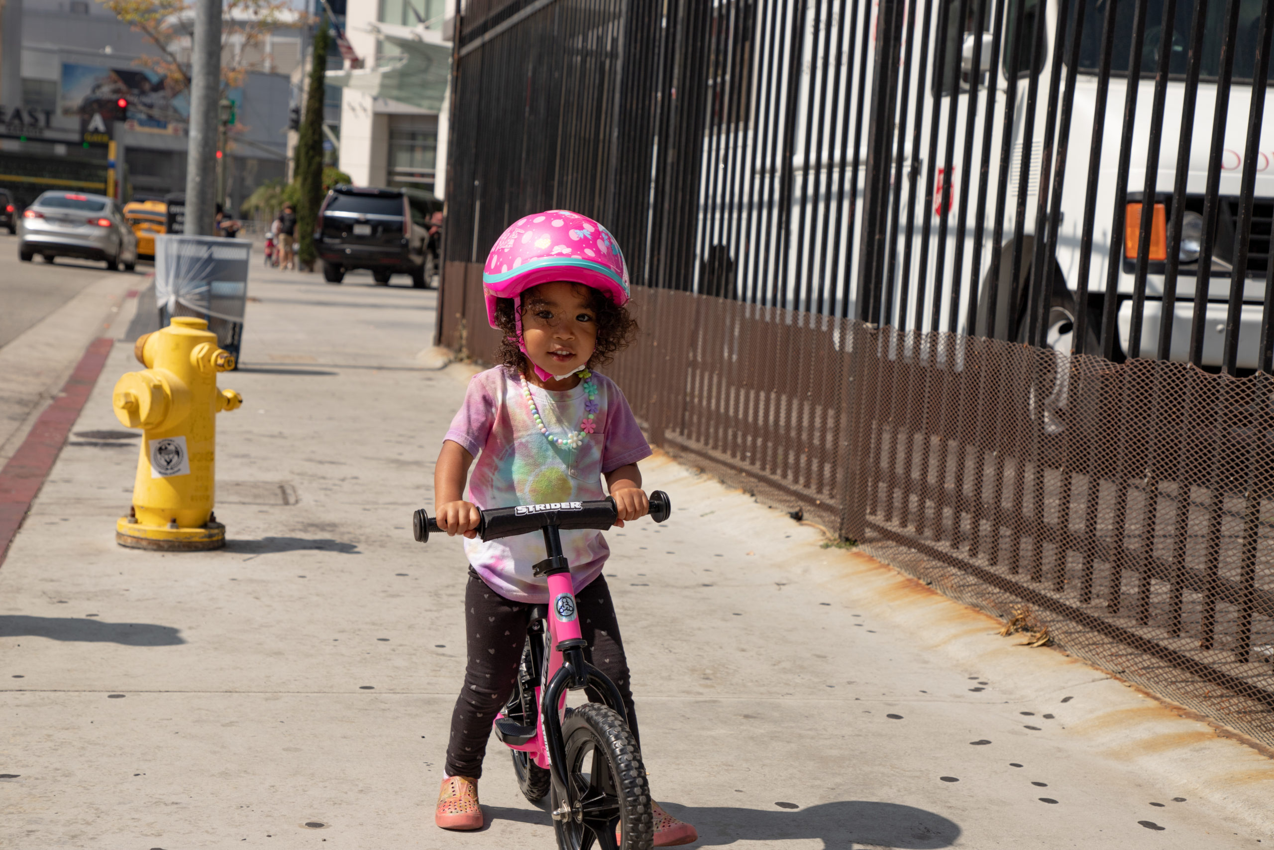 Young girl riding on sidewalk on pink 12 sport