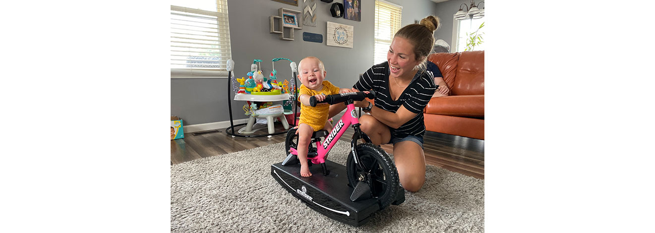 Mom holding baby on pink 2-in-1 Rocking Bike