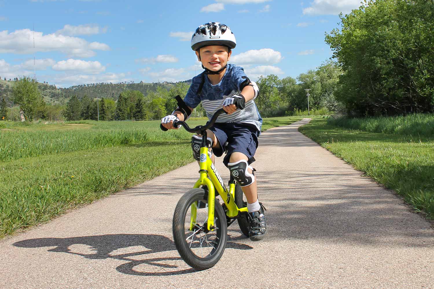 A child riding a Strider 14x bike wearing an Elbow and Knee pad set