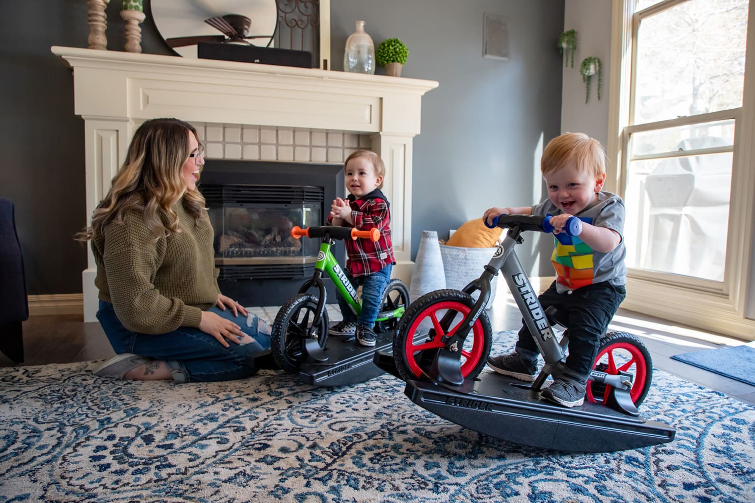 Mother watches two babies play on Strider Rocking Bikes