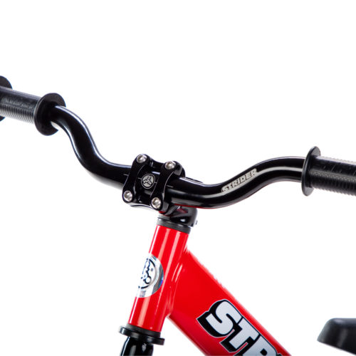 Studio image of Strider Aluminum Riser Handlebar with Grips on red 12 Sport - close-up angle view