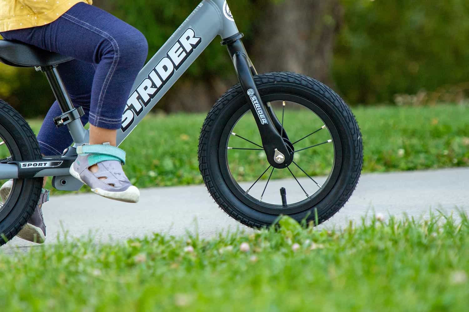 A close up of a gray Strider 12 balance bike equipped with high-traction wheels