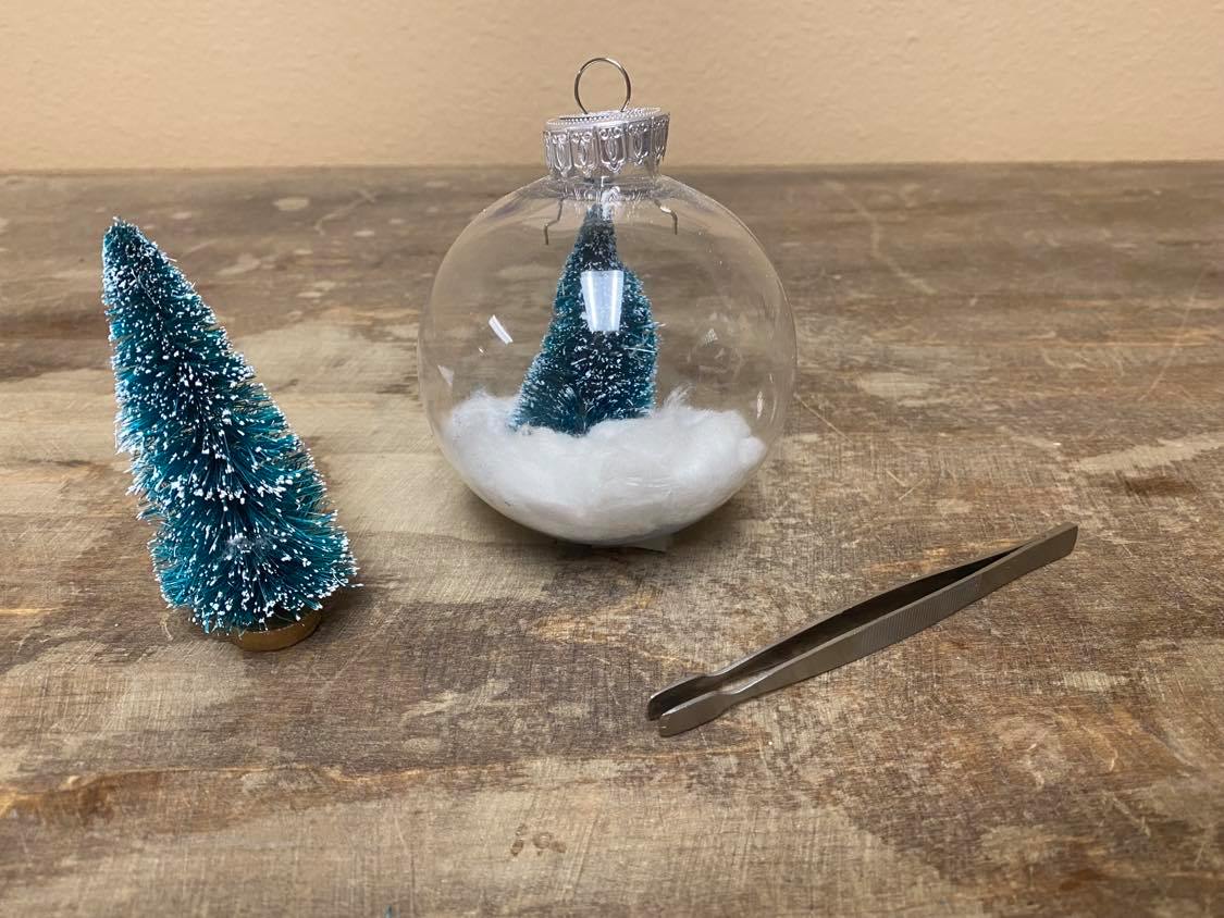 Mini Christmas tree and cotton balls inside a glass ornament 