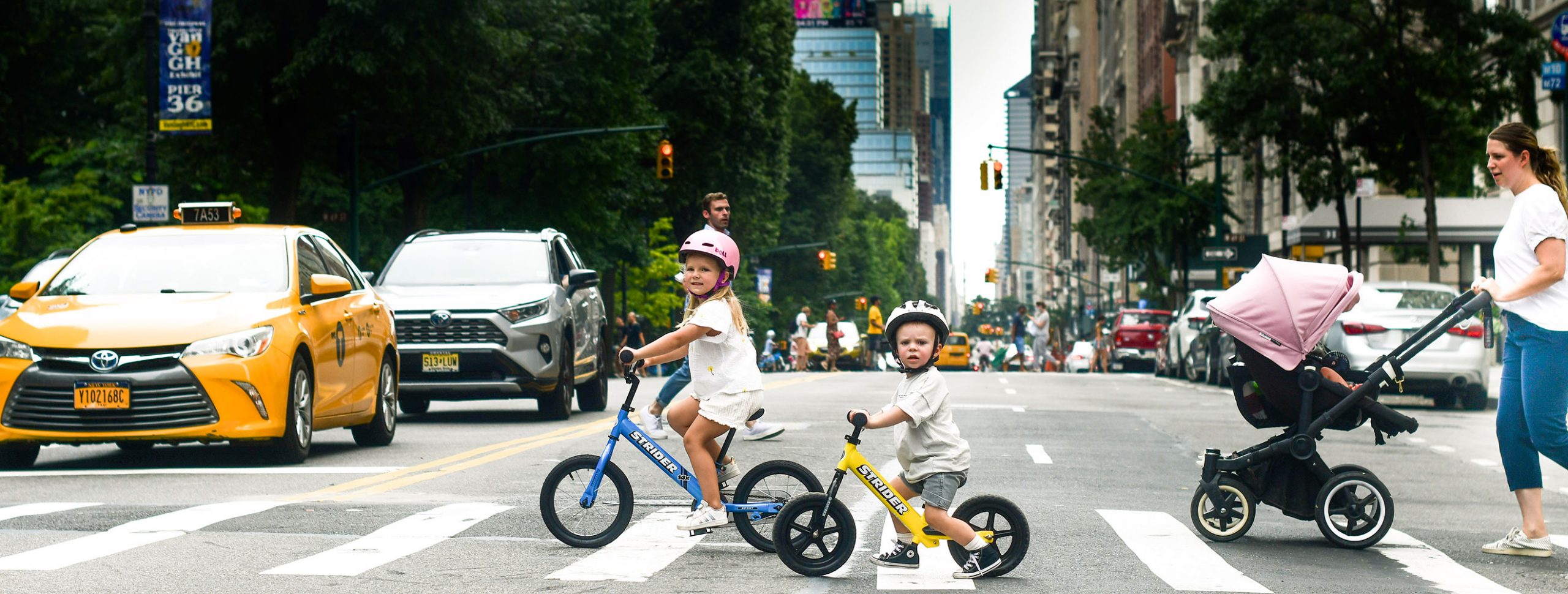 Children ride their Strider Bikes across a busy street in New York