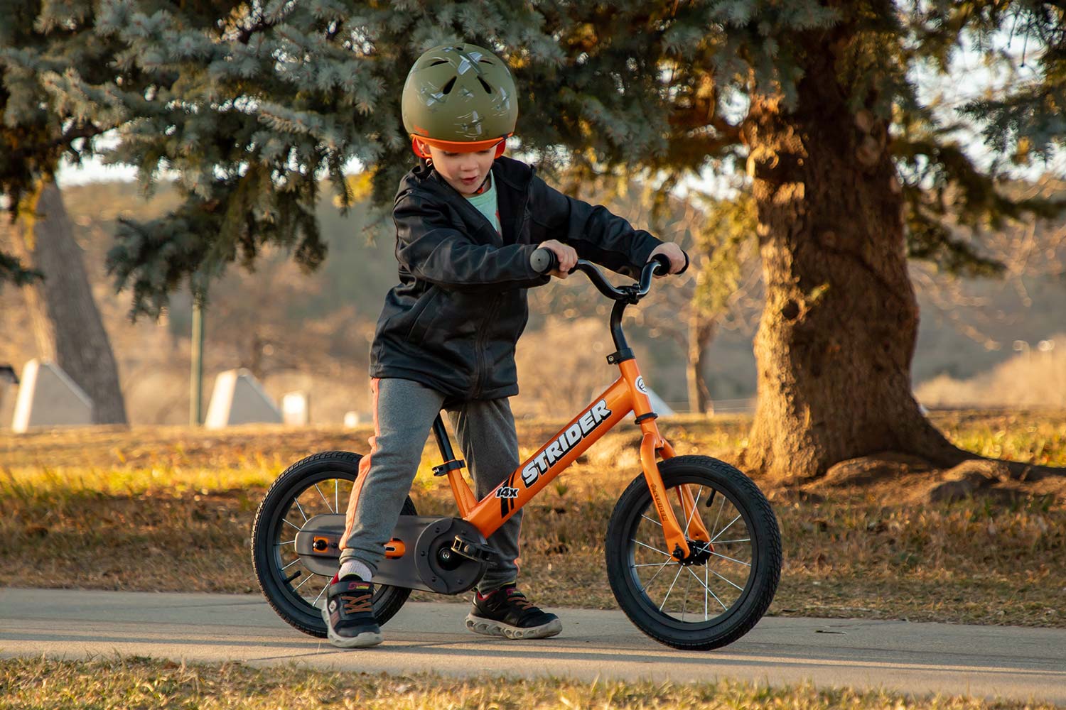 A boy on a tangerine Strider 14x Sport bike with a Strider Standard Stem holding the handlebars